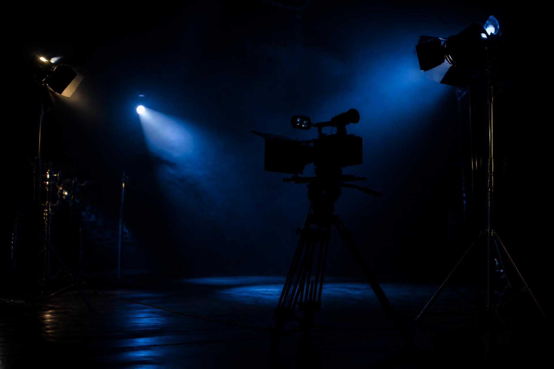 Dark cinematic production stage lit with blue light and gold highlights
